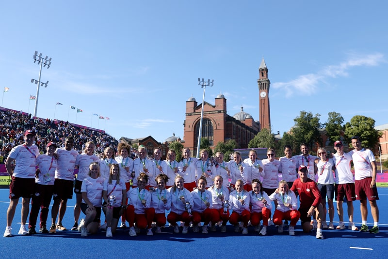 Athletes and support staff on hockey pitch