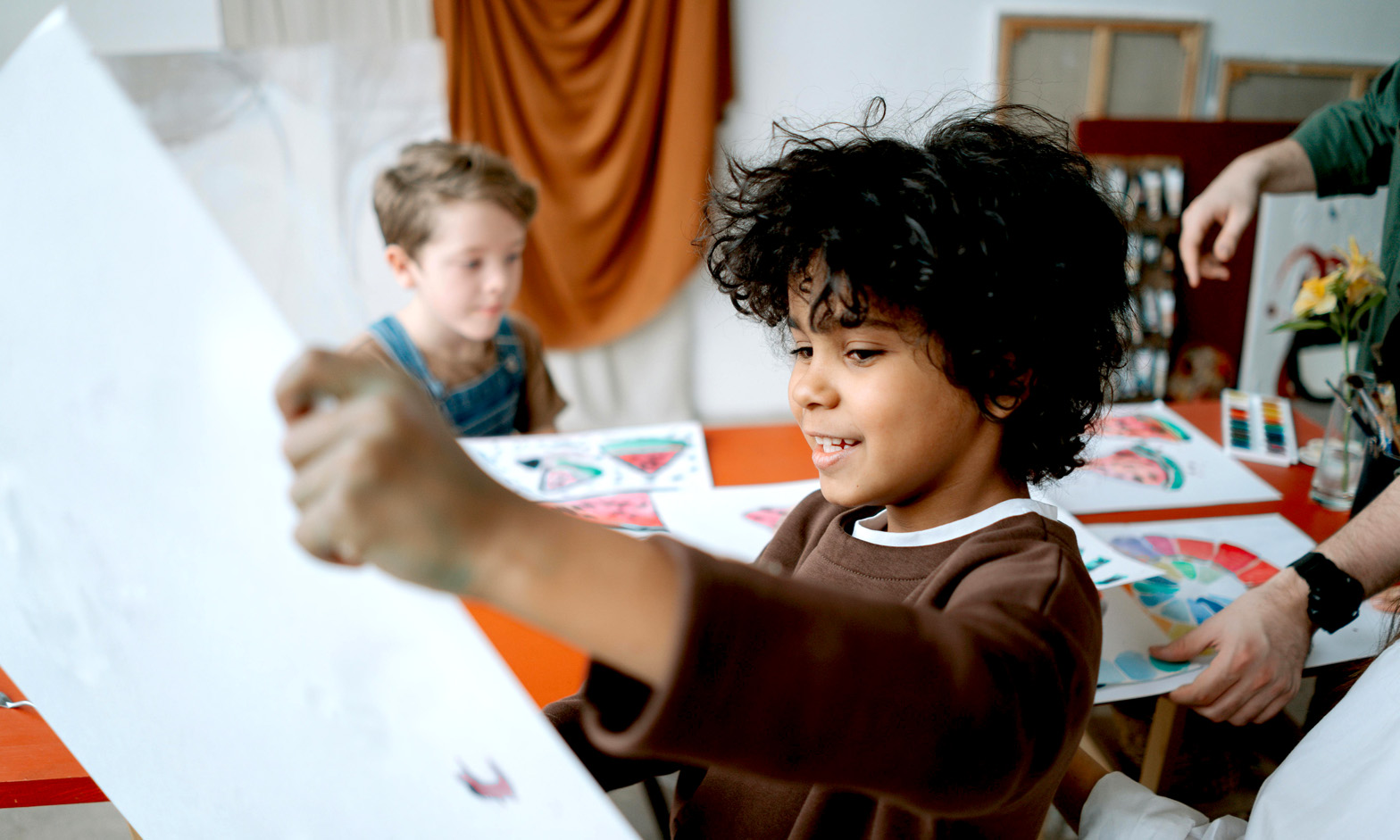 Young boy in an art class holding up his painting to look at